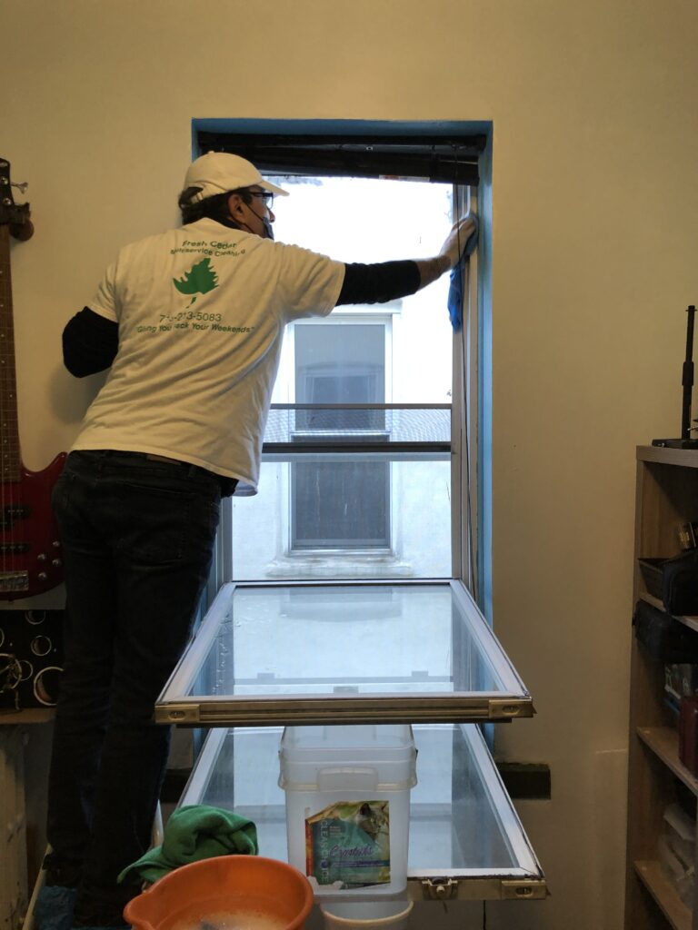 A man cleaning the window wearing a white tshirt